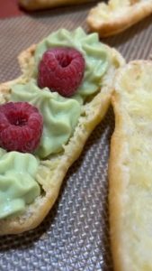 éclair garni de crème pâtissière pistache et de framboises fraîches